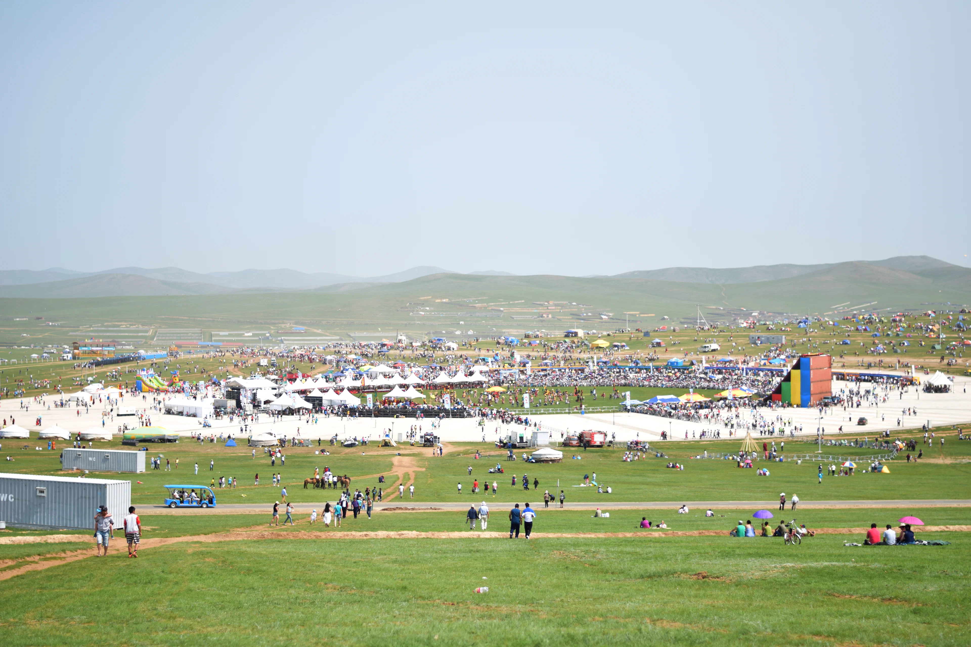 Crowds and tents on the grassy festival grounds