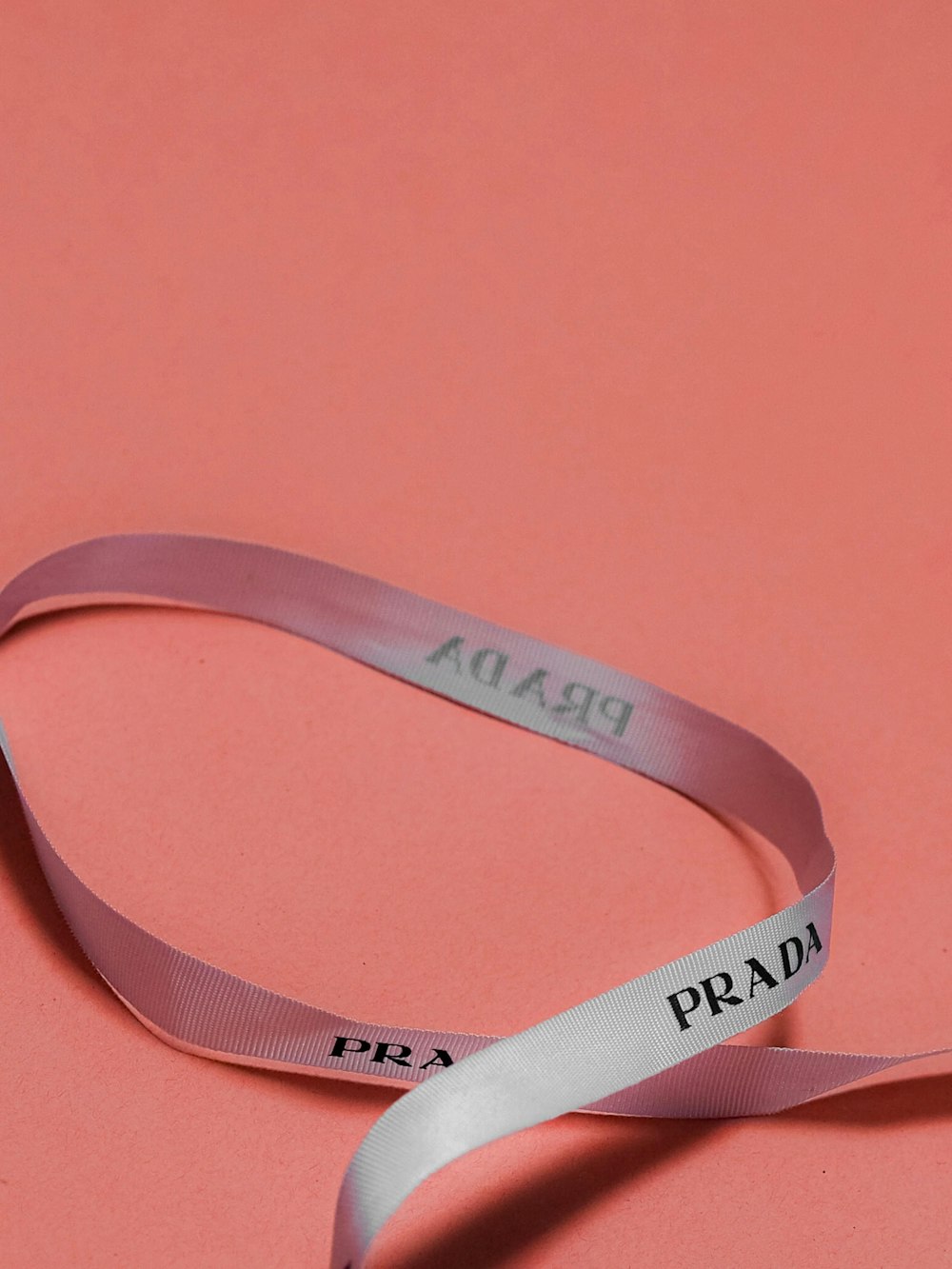 a pink ribbon with the word prada on it