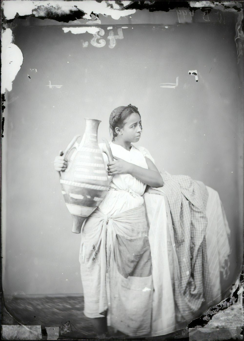 grayscale photo of girl in dress holding vase