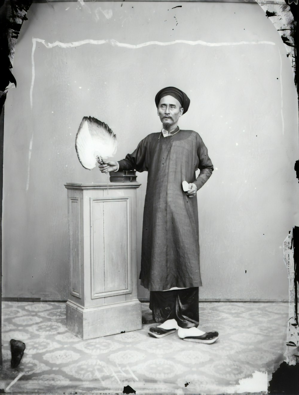 grayscale photo of woman in dress standing near wall