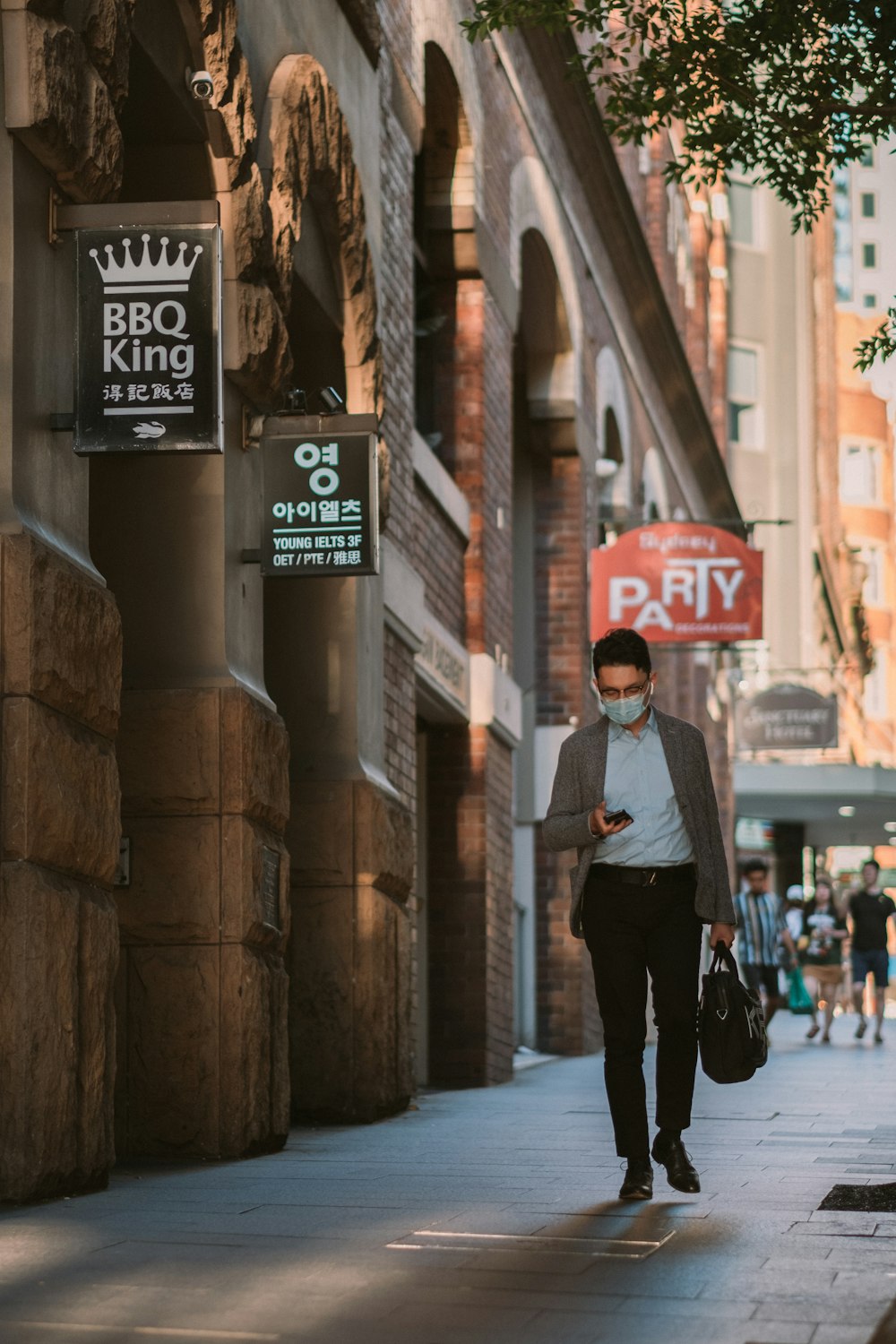 man in black jacket and black pants walking on sidewalk during daytime