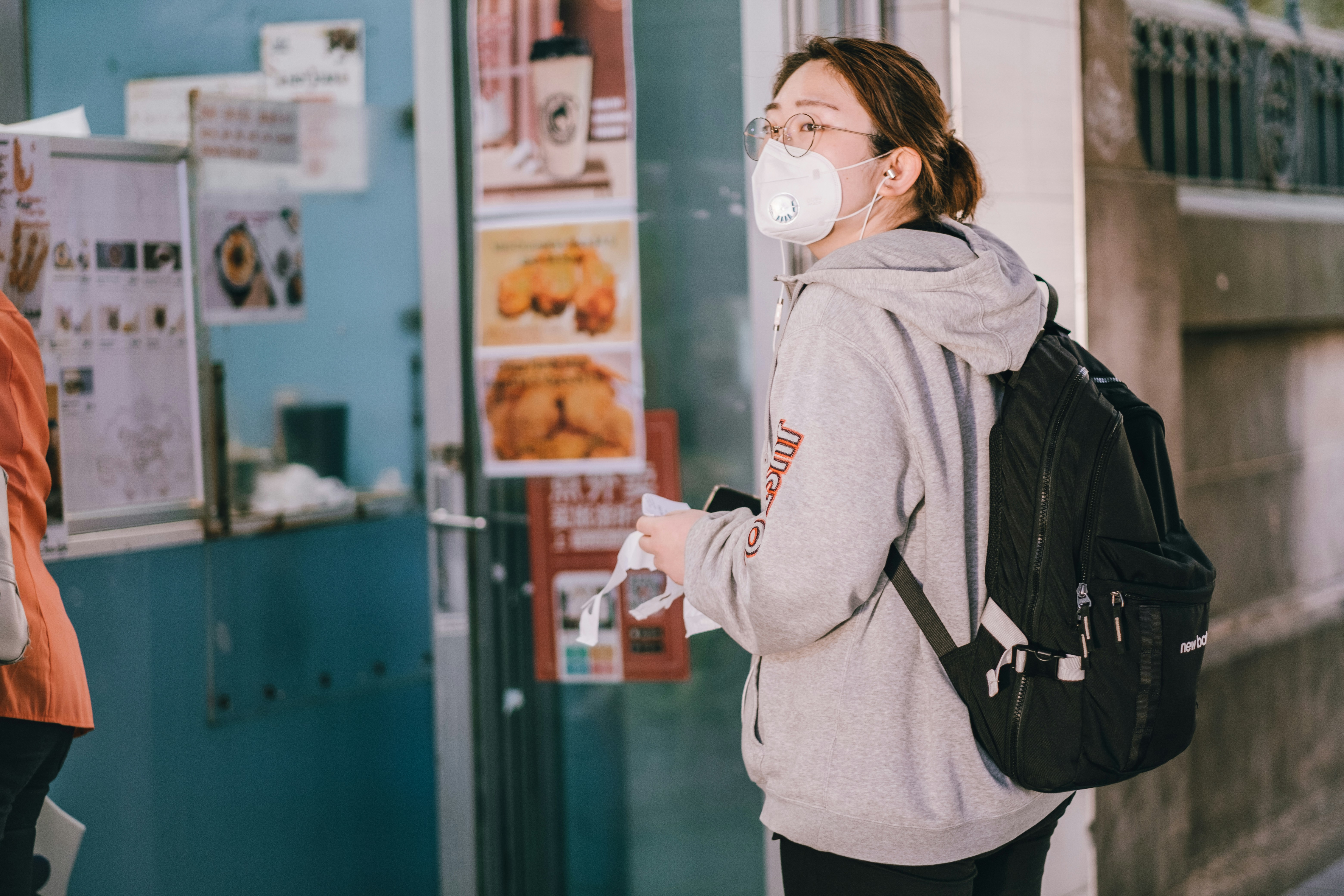 woman in face mask waiting in a line to get takeaway food during the coronavirus lockdown