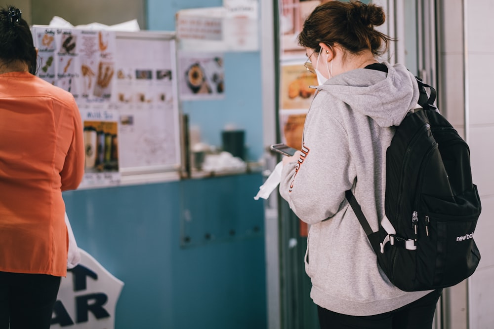 woman in gray hoodie standing in front of white and blue wall