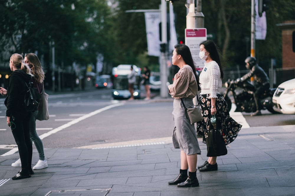 woman in beige coat standing on sidewalk during daytime