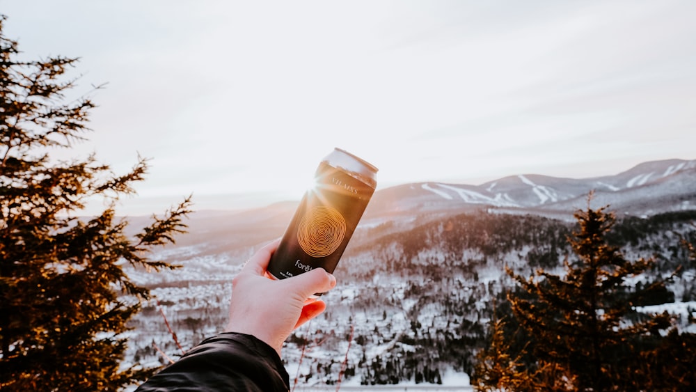 person holding brown plastic cup with brown liquid