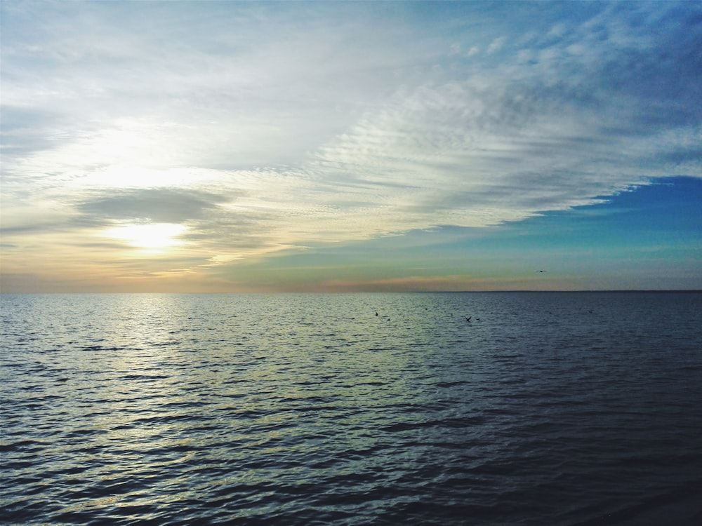 body of water under cloudy sky during sunset