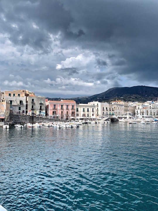 white and brown concrete building near body of water under cloudy sky during daytime in Lipari Italy