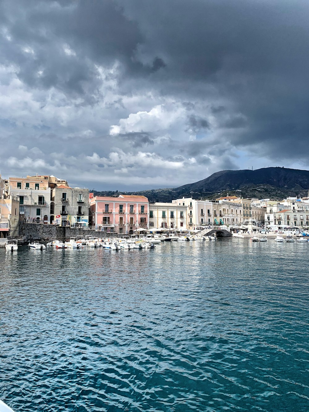 white and brown concrete building near body of water under cloudy sky during daytime