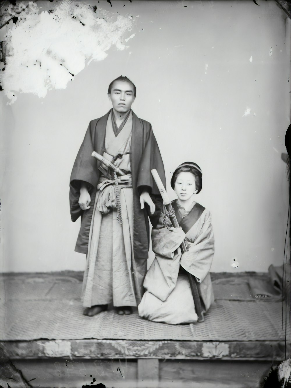 woman in kimono standing beside boy in thobe