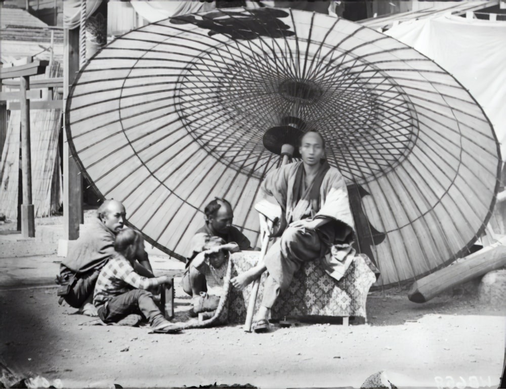 grayscale photo of 2 women and 2 children under umbrella