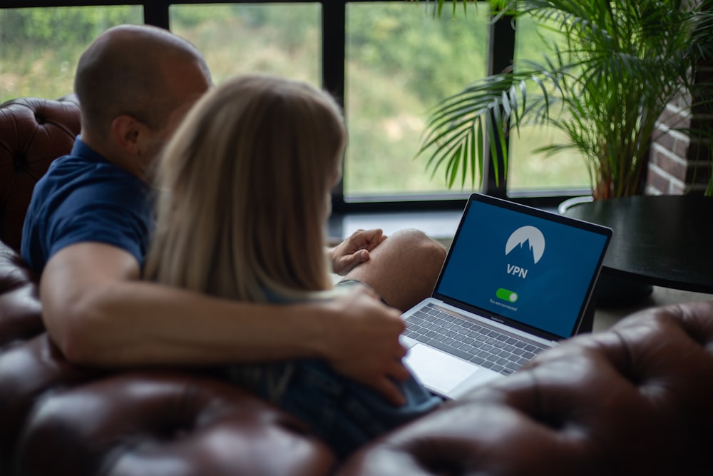 man and woman sitting on chair in front of macbook pro