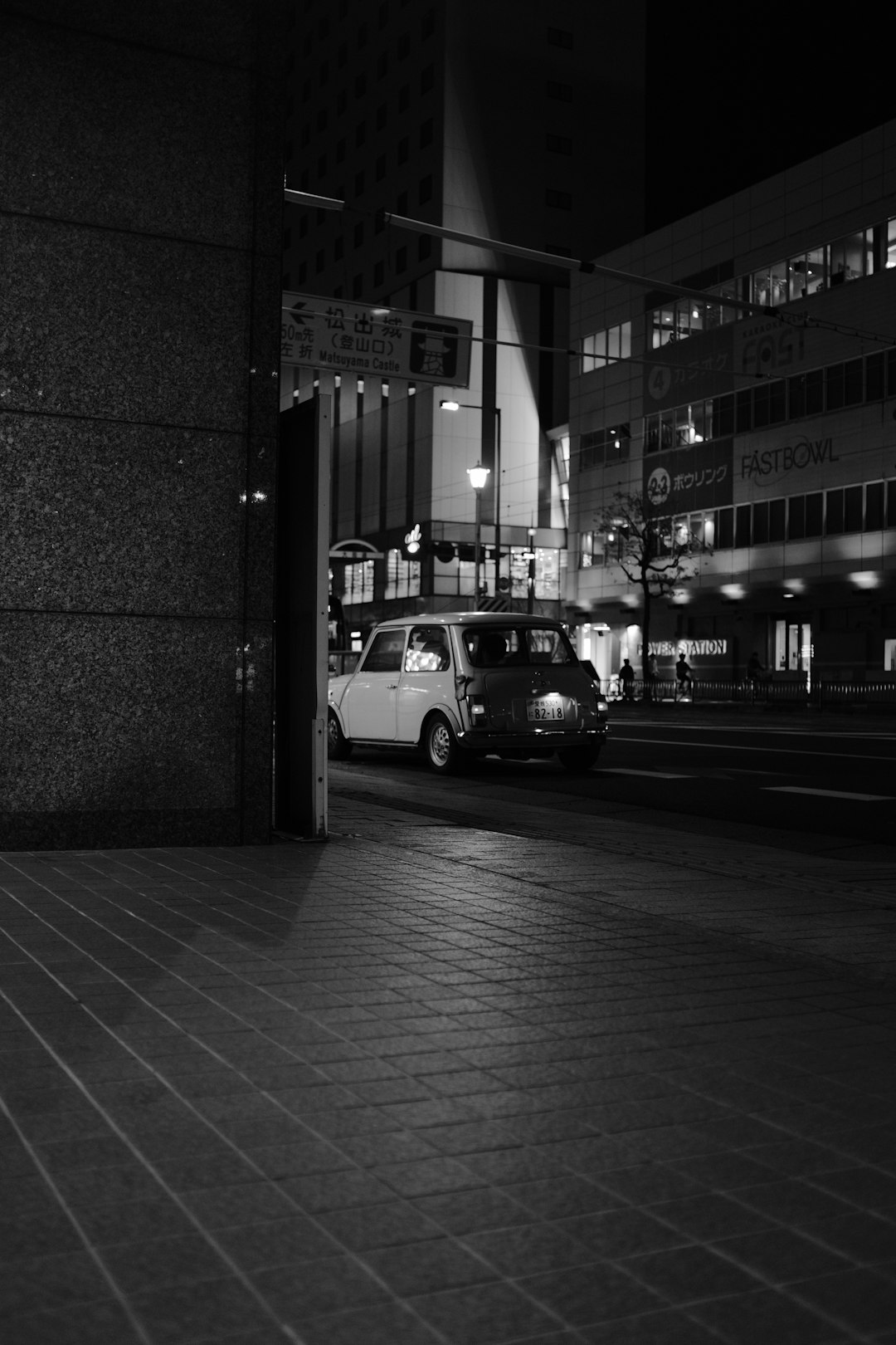 grayscale photo of cars parked beside building