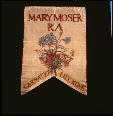 A decorative banner featuring the name Mary Moser with R A beneath it. Below the text, there is an artistic depiction of a floral arrangement featuring blue, pink, and red flowers. The banner has a pointed end with the words 'Carnation Lily Rose' at the bottom.