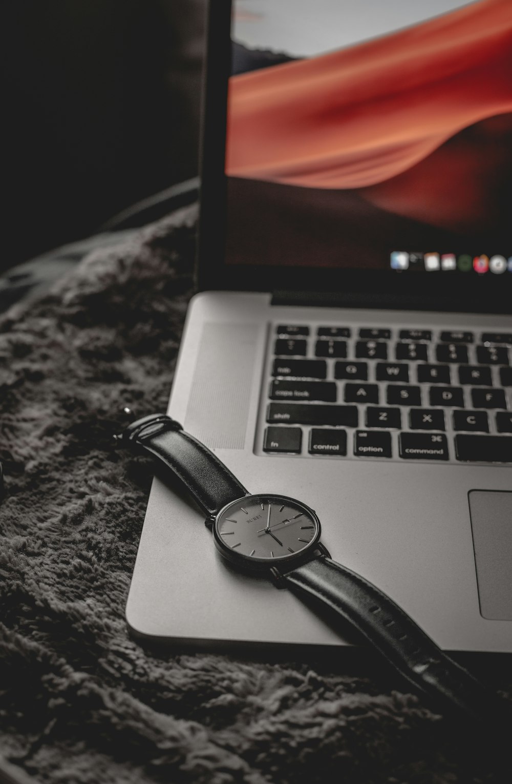 black and silver laptop computer beside black leather strap round analog watch