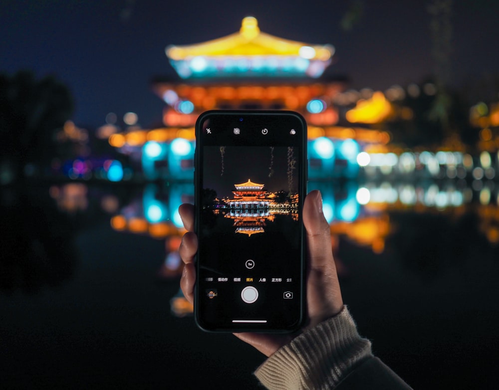 person holding iphone taking photo of yellow and white tower