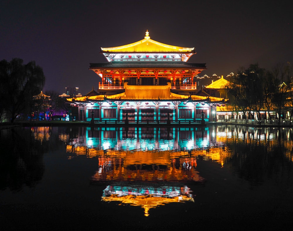 brown and white temple near body of water during night time