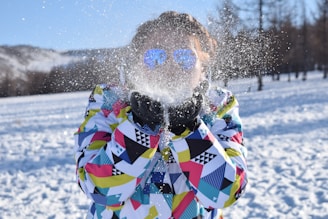 Close-up of a sleek designer ski jacket with intricate details and vibrant colors, laid out on soft snow.