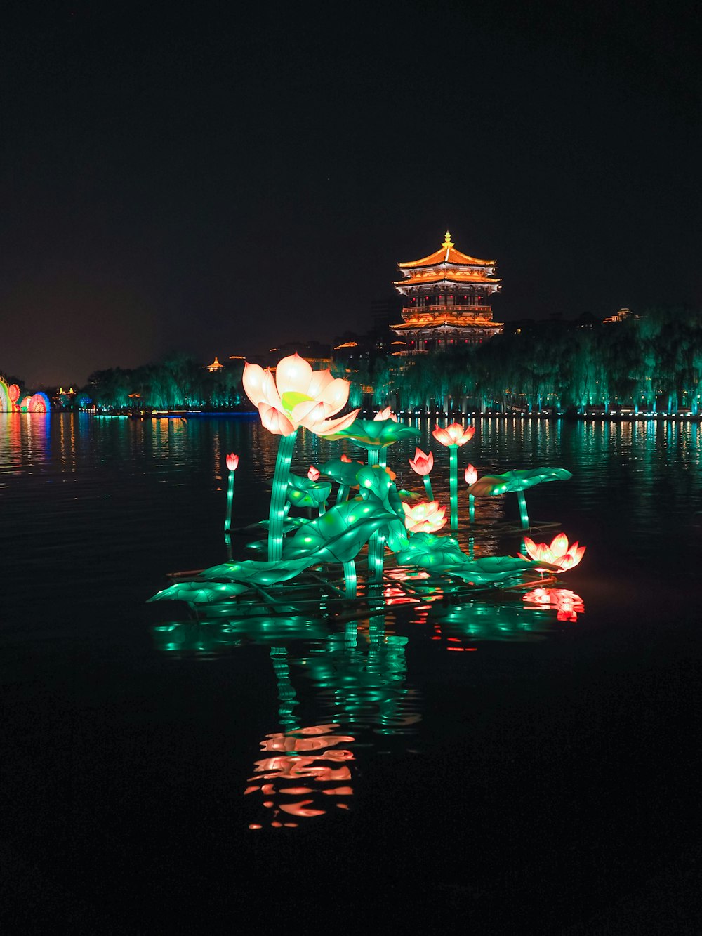 green and yellow string lights on body of water during night time