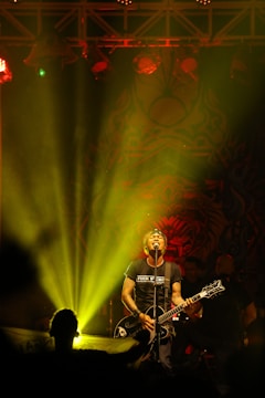 Close-up of Joel La Clave performing passionately on stage with vibrant city lights behind.