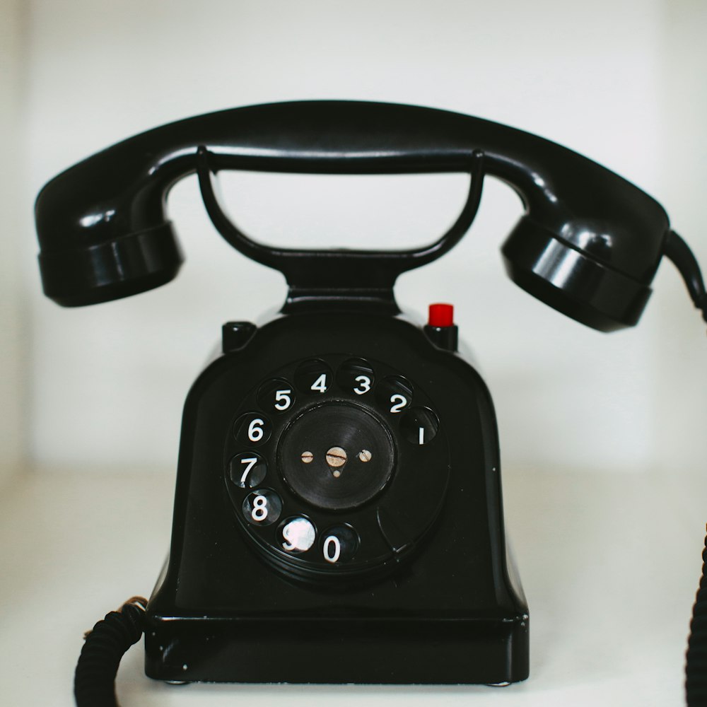 black rotary telephone on white table