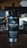A large black and silver coffee dispenser with the branding 'True Stone Coffee Roasters' displayed prominently. Below the logo, the phrases 'Fresh. Local. Independent.' and 'Fresh Coffee. Cool Beans.' are printed. In the background, a blurred coffee shop setting with dark cabinets and various equipment is visible.