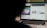 A partially obscured view of a laptop screen displaying two separate browser tabs. The left tab shows a children's cartoon video, while the right tab appears to be a webpage with photos and metadata, possibly related to stock photography. The foreground is dark, highlighting the screen's content.