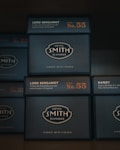 Several stacked boxes of Steven Smith Teamaker tea, labeled with the blend 'Lord Bergamot' and 'Kandy'. The packaging is dark with orange and white text, highlighting blend numbers 55 and 23.