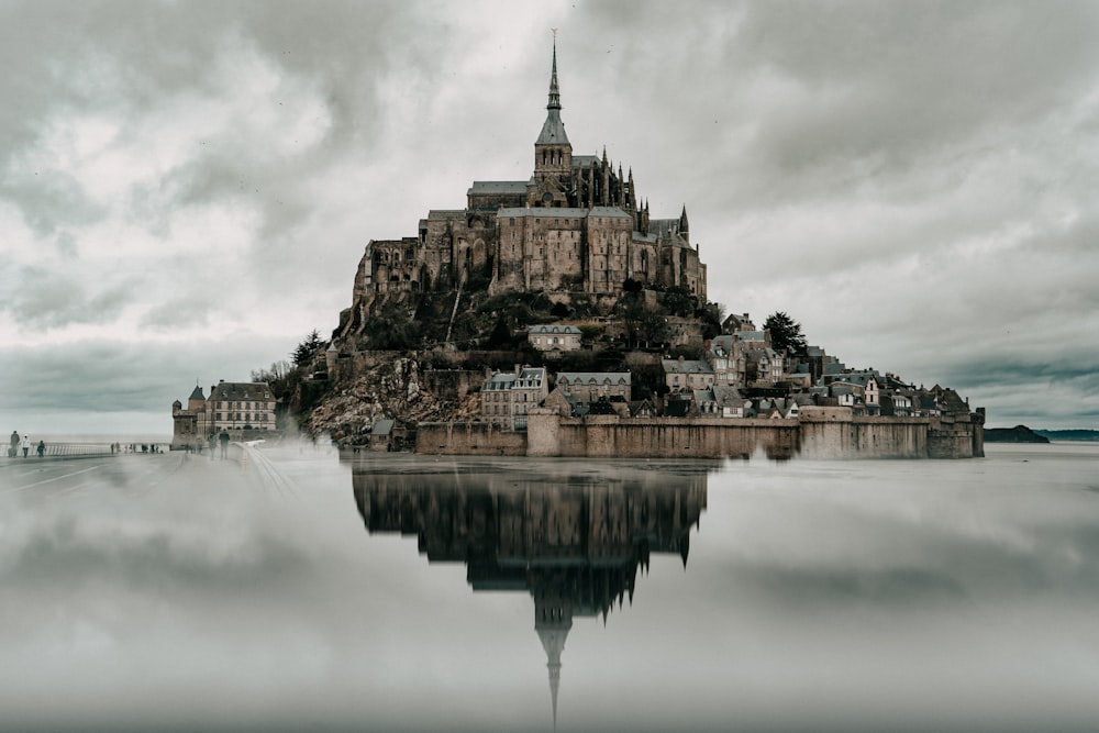 Edificio in cemento marrone e nero vicino allo specchio d'acqua sotto il cielo nuvoloso durante il giorno