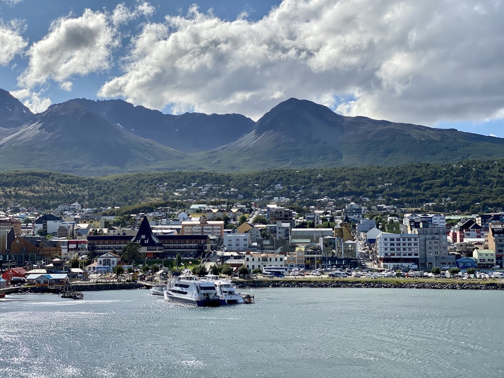 white boat on body of water near city buildings under white clouds and blue sky during