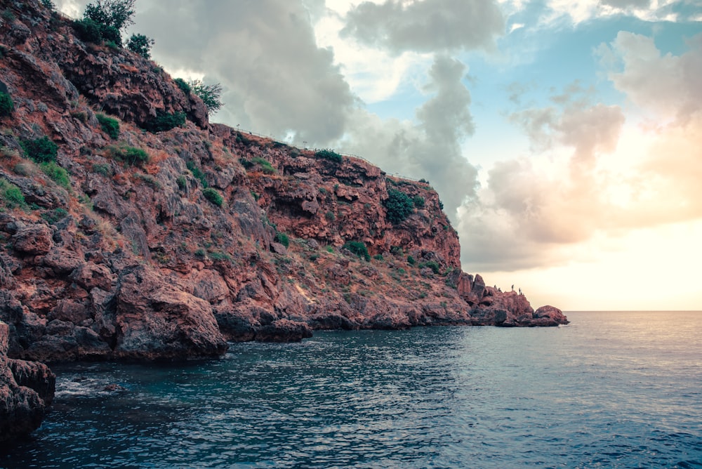 brown rock formation on sea under white clouds during daytime