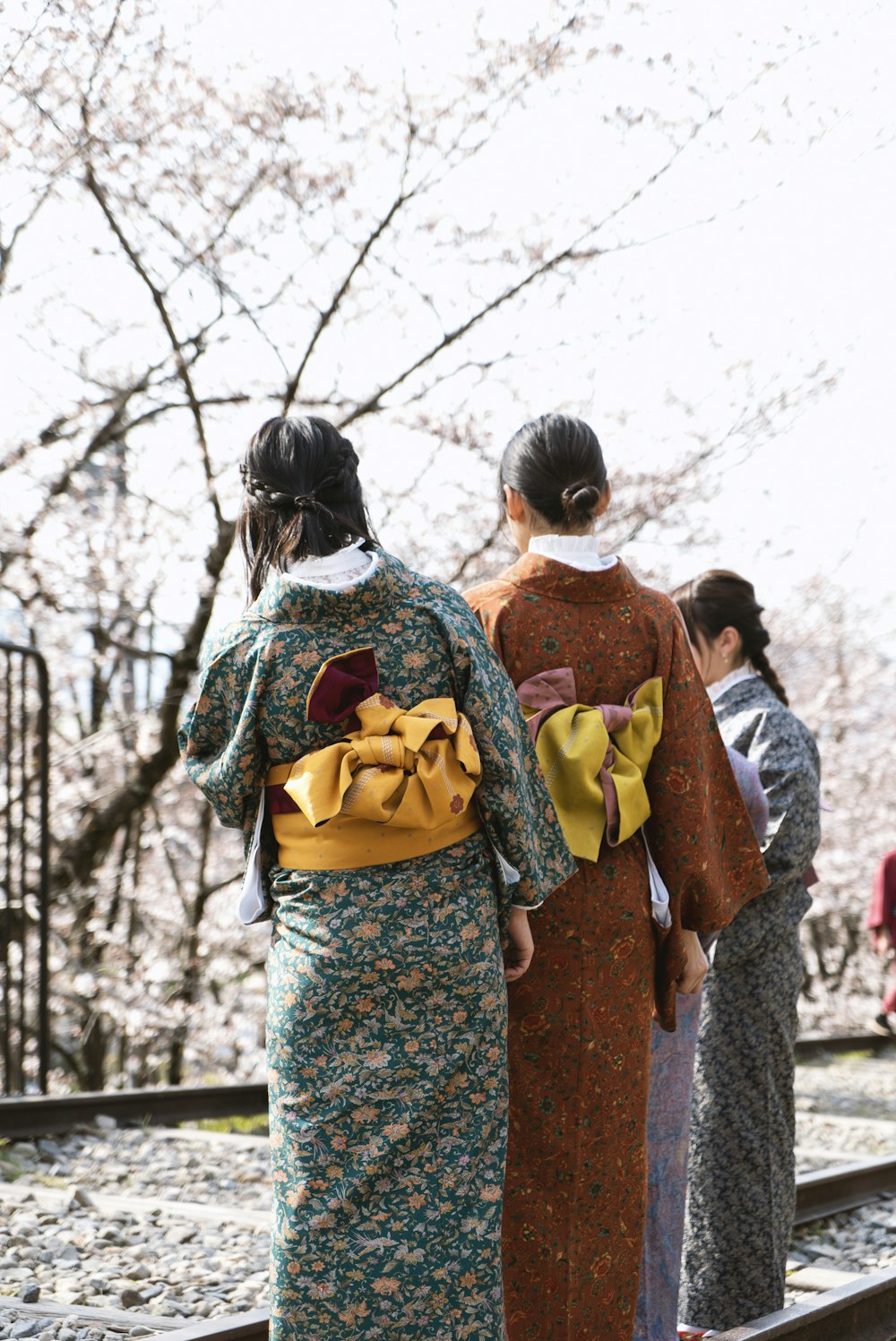 2 women in kimono standing near trees during daytime