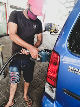 A smiling person refueling a hydrogen car at a modern station.