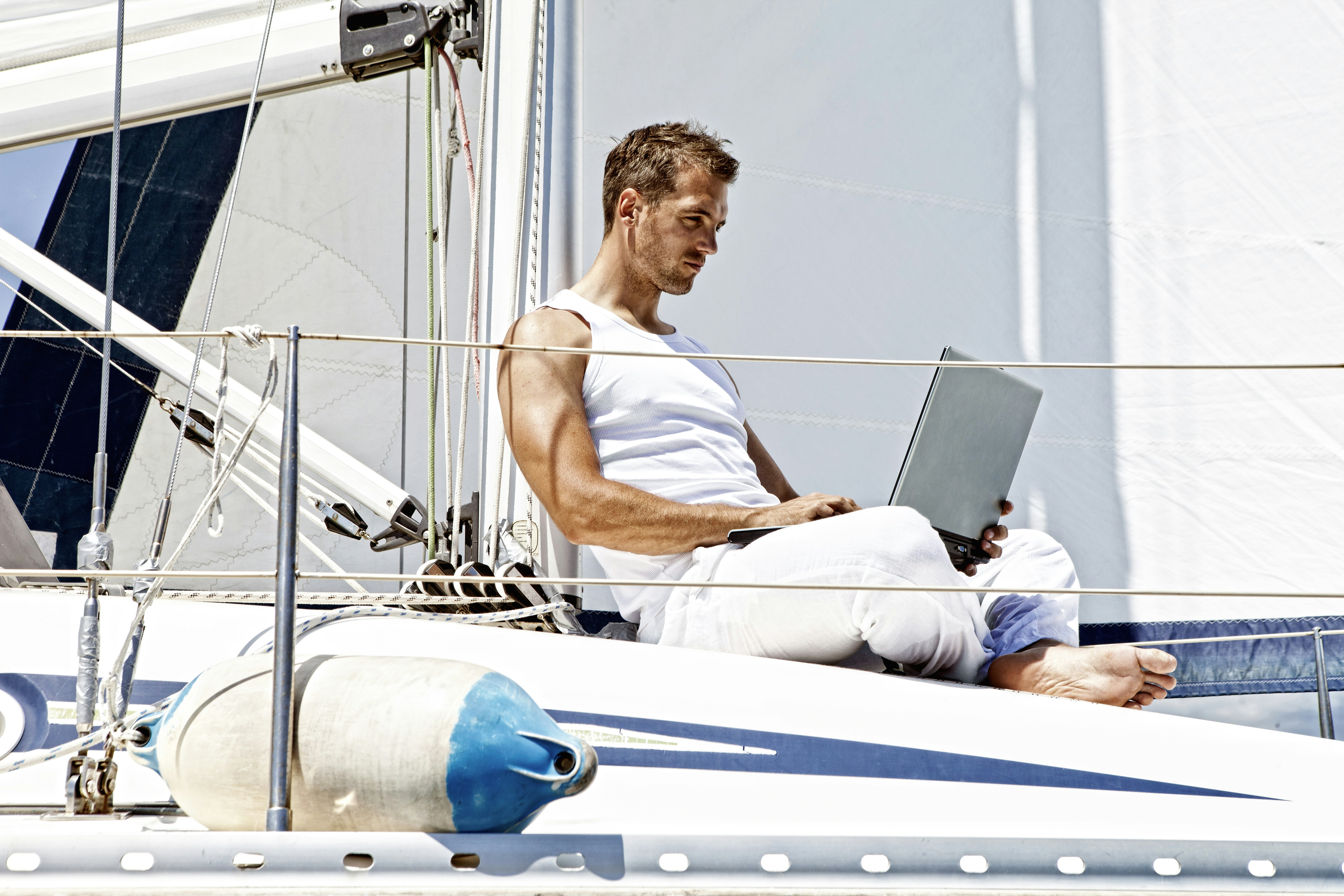 man in white tank top sitting on white boat during daytime