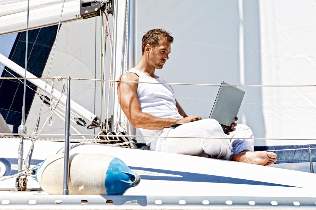 man in white tank top sitting on white boat during daytime