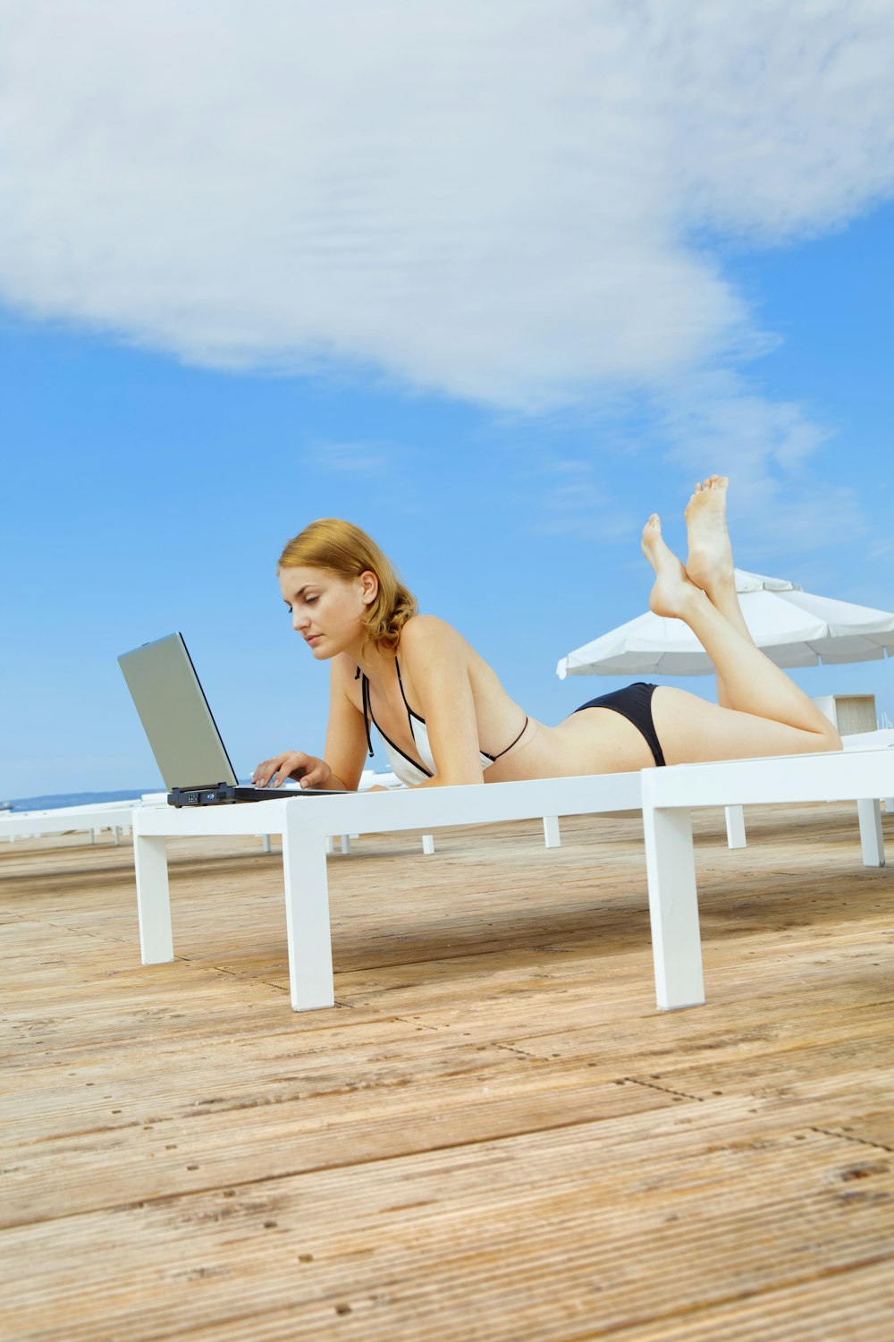 woman in black bikini lying on white wooden bench