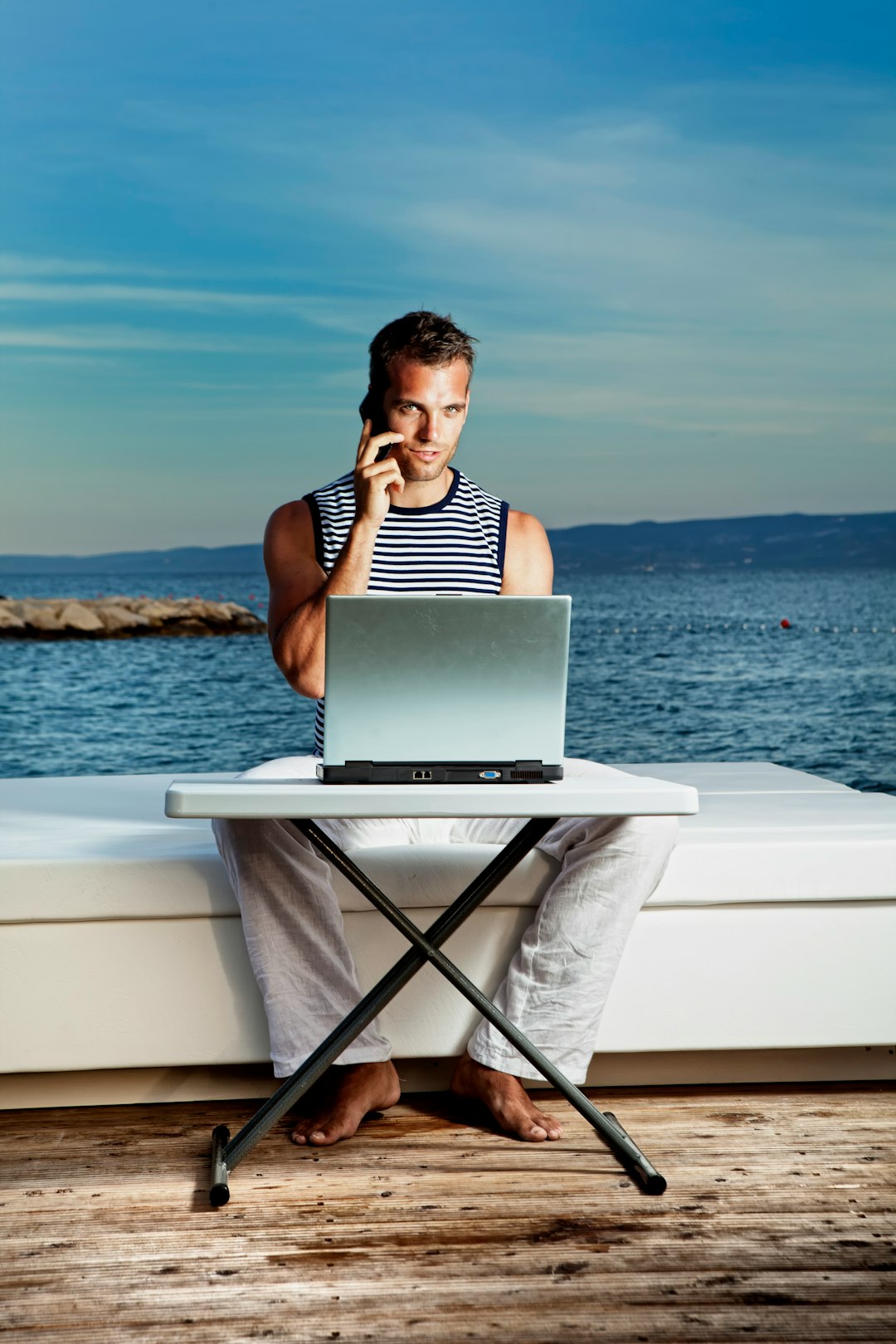 woman in black and white stripe tank top sitting on white chair using macbook air