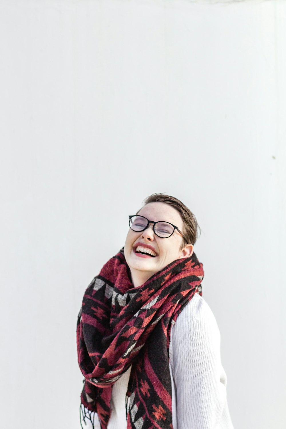 woman in white sweater wearing brown and black scarf and black framed eyeglasses