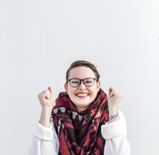 woman in white sweater wearing red scarf and black framed eyeglasses