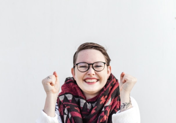 woman in white sweater wearing red scarf and black framed eyeglasses