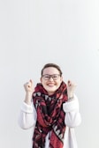 woman in white sweater wearing red scarf and black framed eyeglasses