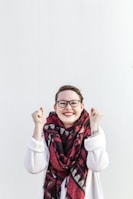 woman in white sweater wearing red scarf and black framed eyeglasses