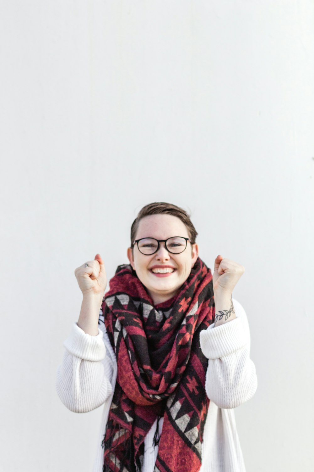 赤いスカーフと黒いフレームの眼鏡をかけた白いセーターの女性