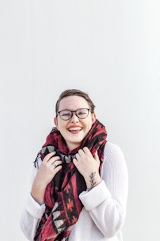 woman in white sweater wearing red scarf and black framed eyeglasses