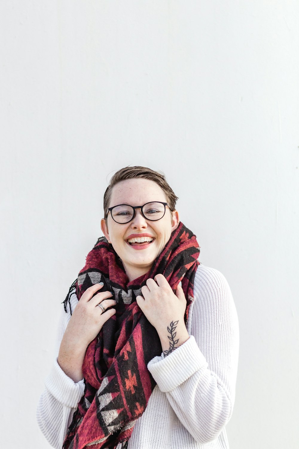 woman in white sweater wearing red scarf and black framed eyeglasses