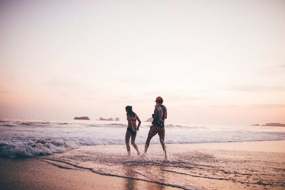 2 women walking on beach during daytime