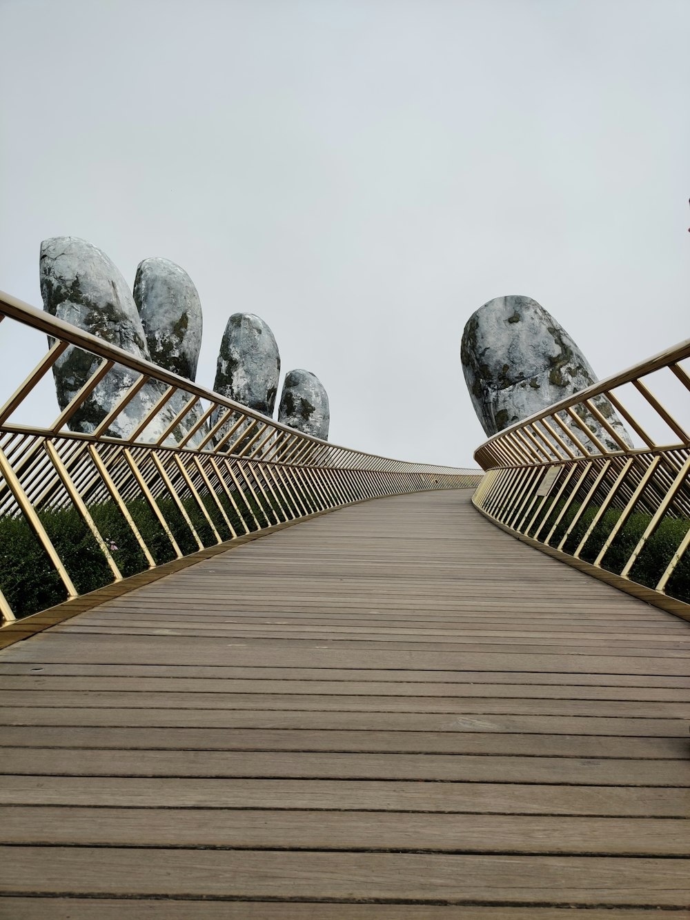 灰色のコンクリート像と茶色の木製の橋