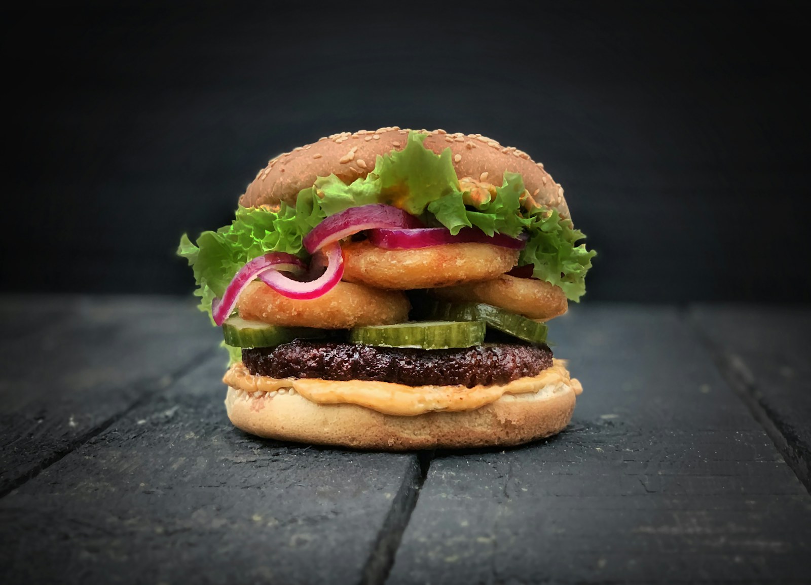 A smash burger with lettuce and melted cheese on a dark board