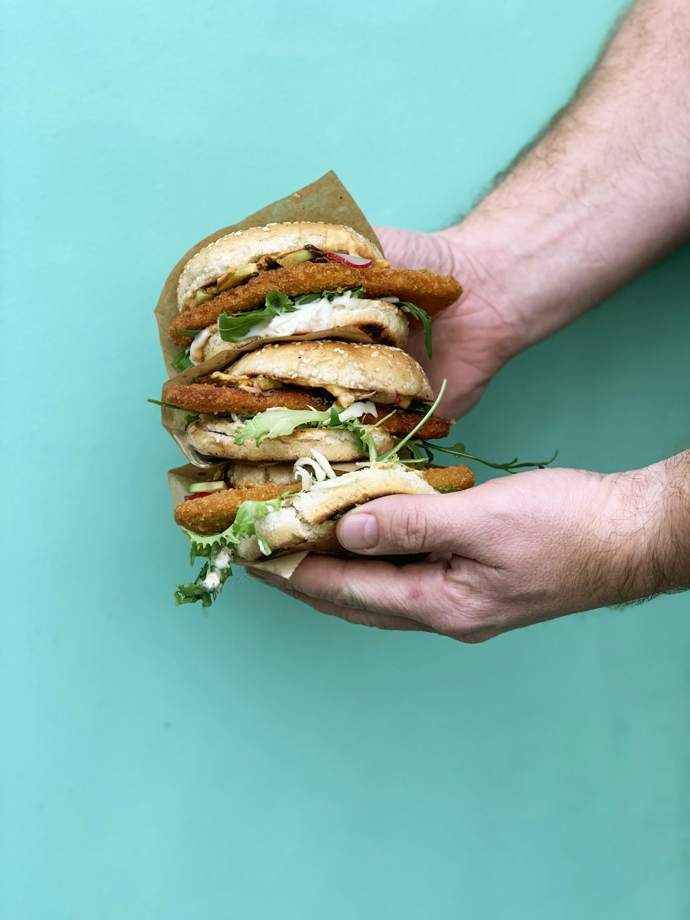person holding burger with lettuce and tomato