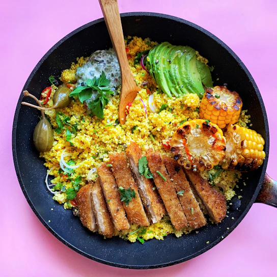 A vibrant Moroccan couscous dish with colorful vegetables and tender meat, served in a rustic ceramic bowl.