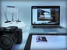 macbook pro beside black dslr camera on white table